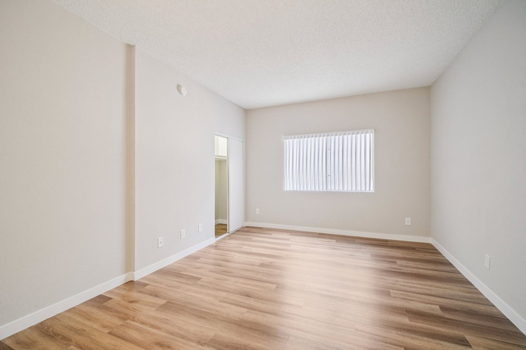 A room with wooden flooring and a window with blinds.