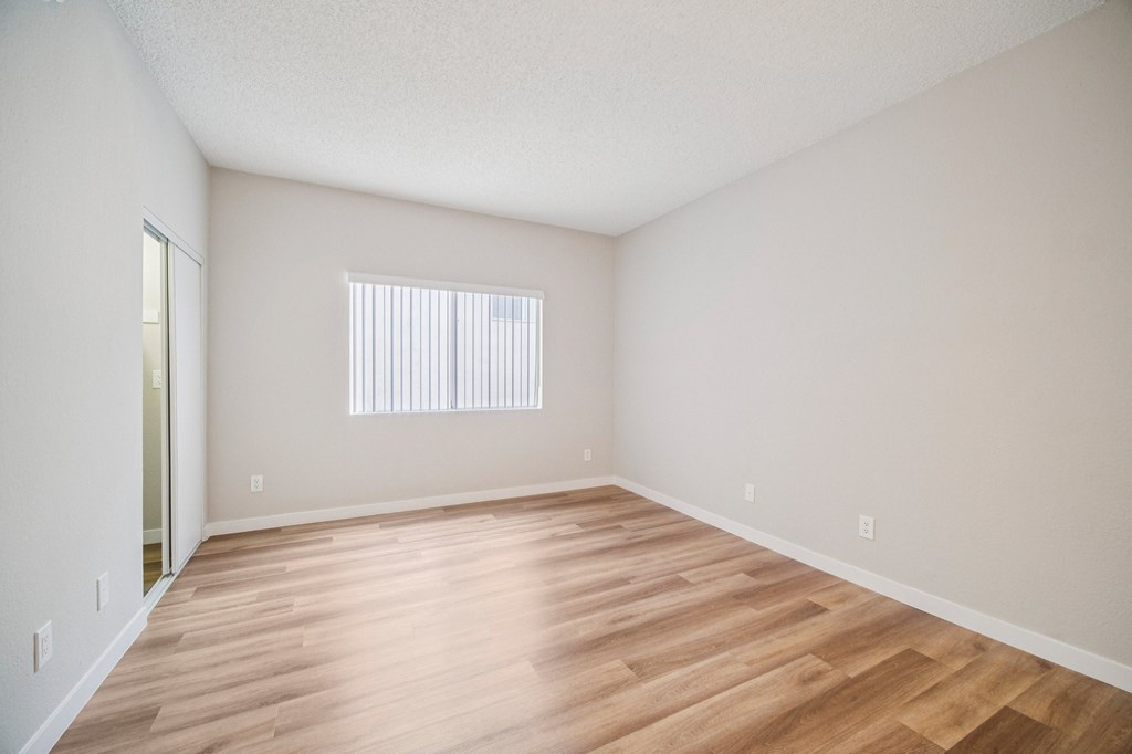 A room with wooden flooring and a window with blinds.