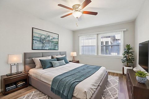 A bedroom with a bed, a ceiling fan, and a window.