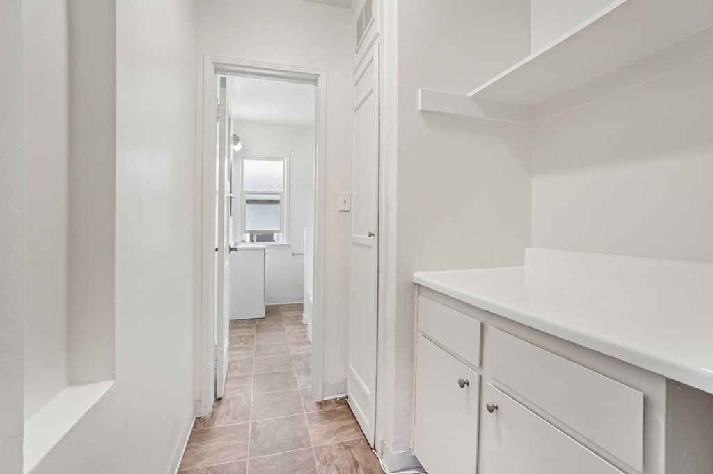 A white kitchen with a refrigerator and cabinets.