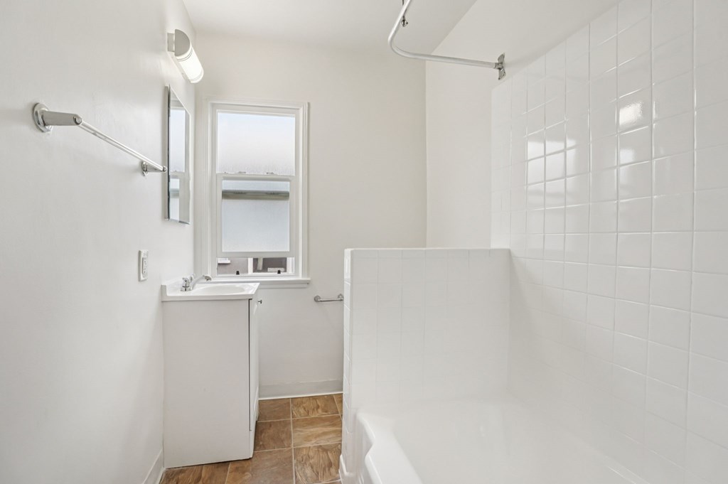 A white bathroom with a shower, sink, and mirror.