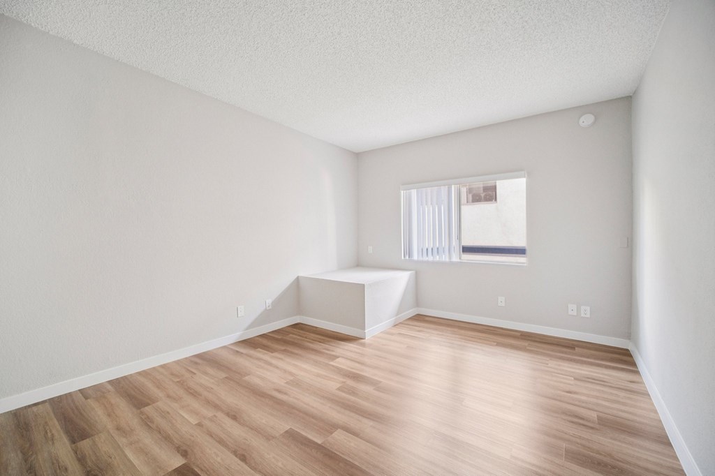 A room with wooden flooring and a window with blinds.