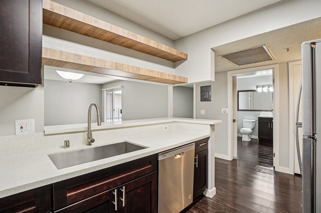 A modern kitchen with dark wood cabinets and a white countertop.
