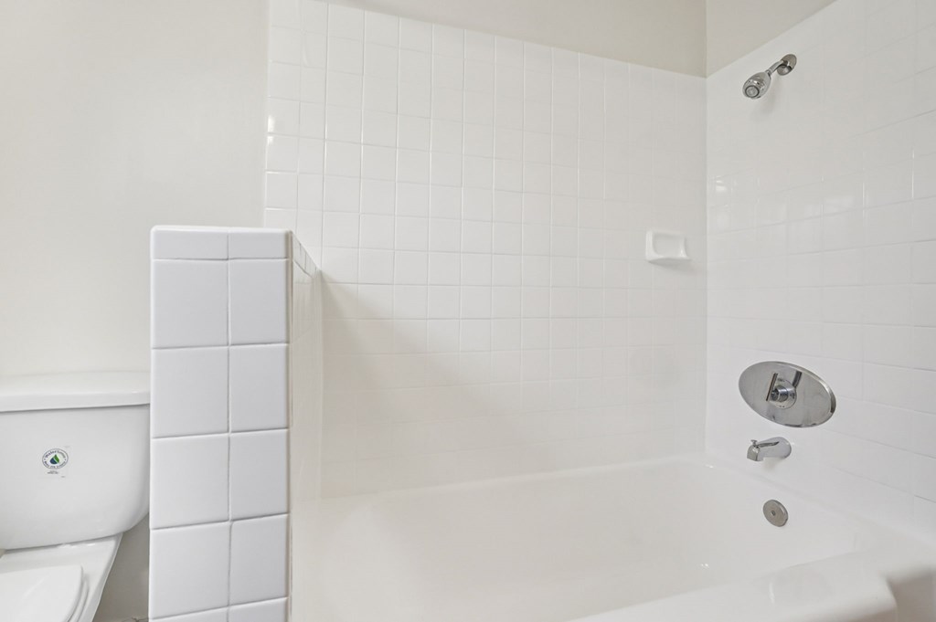 A white bathroom with a toilet, a bathtub, and a shower.