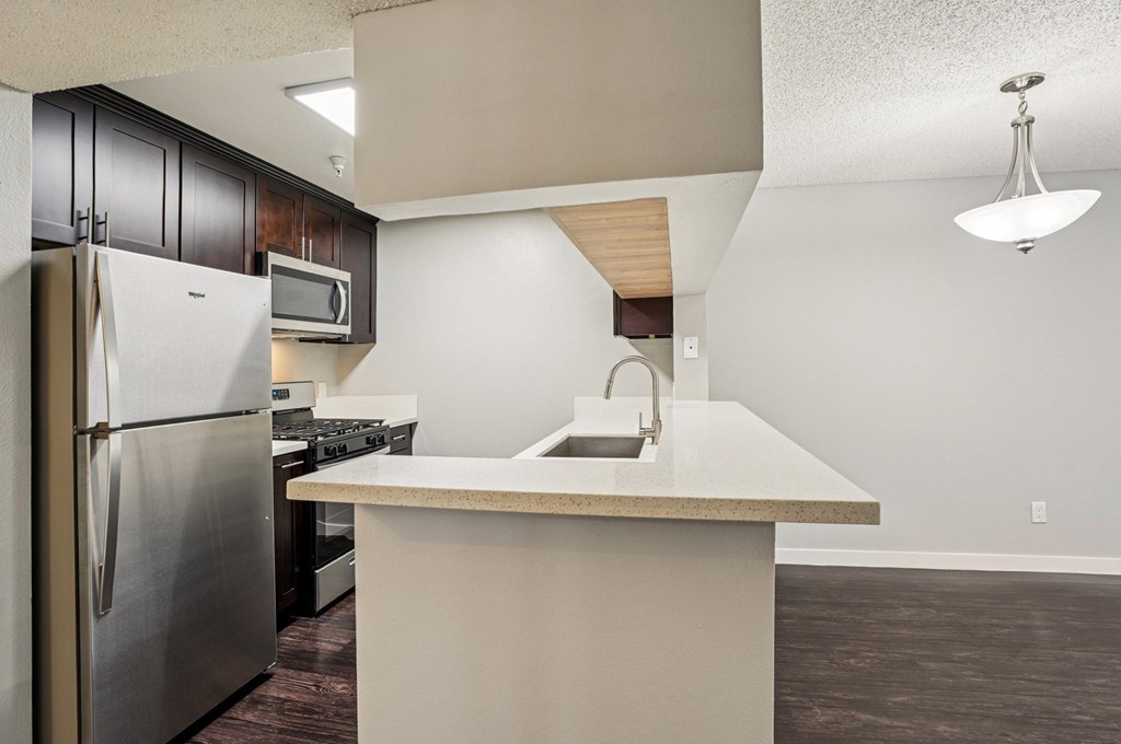 A kitchen with a refrigerator, microwave, and oven.