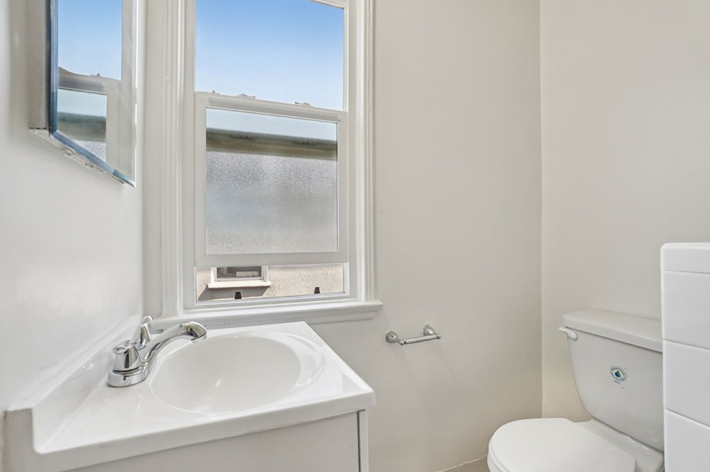 A white sink and toilet in a bathroom with a window.
