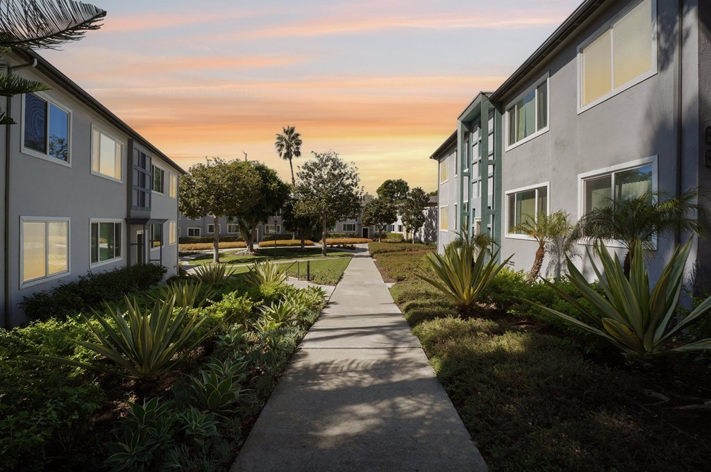 A pathway leads through a landscaped area between two rows of buildings.