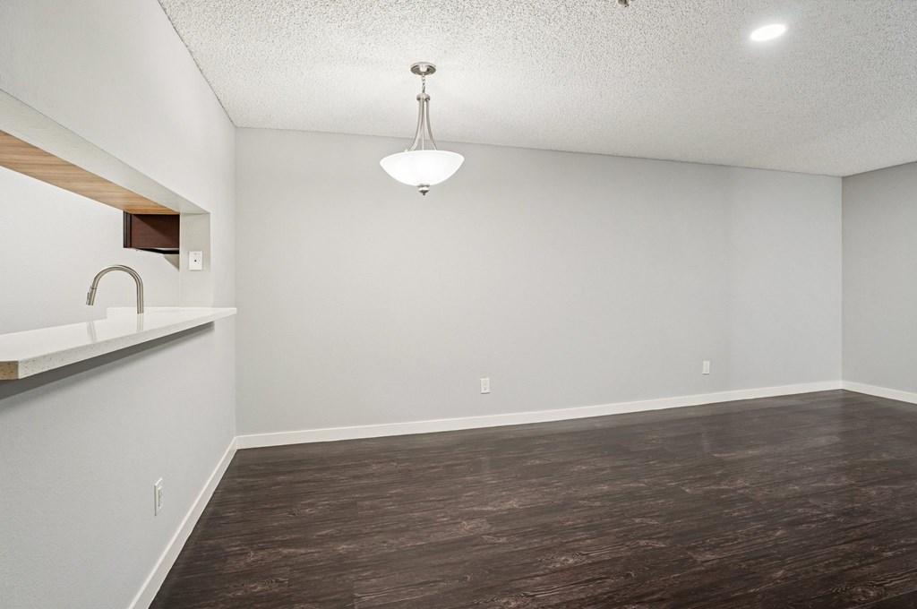 A room with a wooden floor and a white wall with a light fixture hanging from the ceiling.