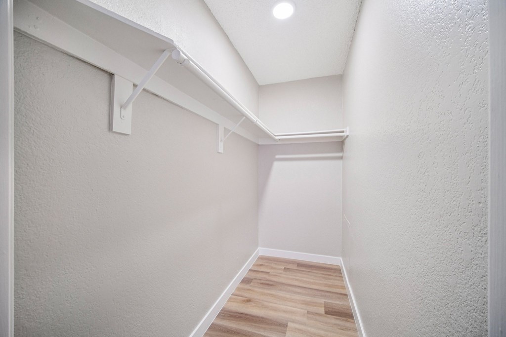 A long hallway with wood floors and white walls.