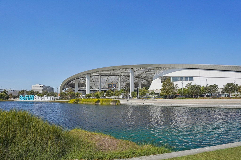 A modern stadium with a curved roof and a body of water in front.