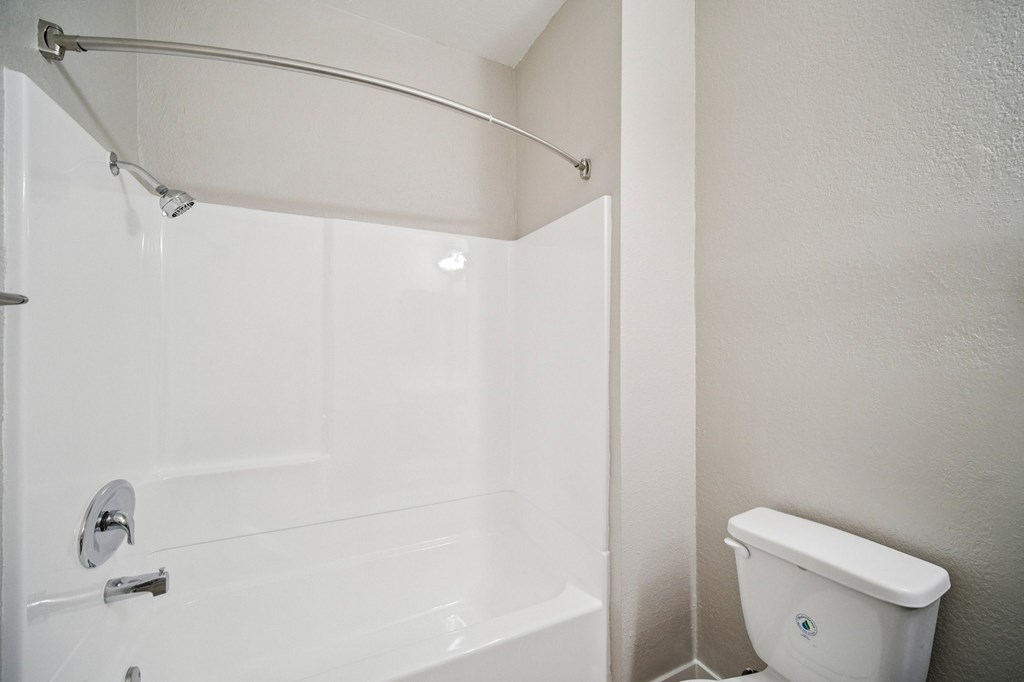 A white bathroom with a toilet and a shower.