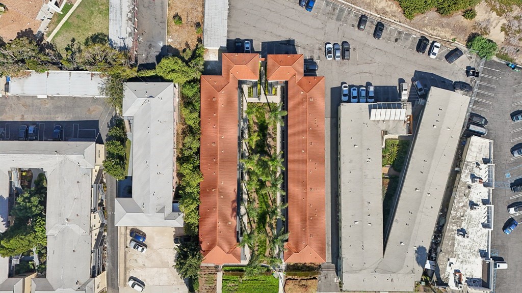An aerial view of a parking lot with cars and a building with a red roof.