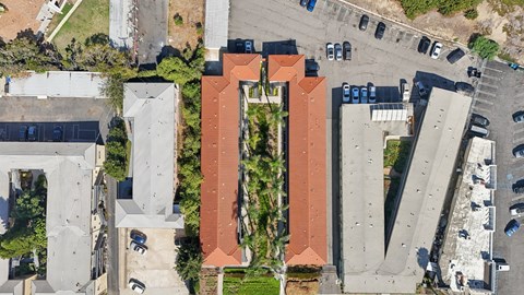 An aerial view of a parking lot with cars and a building with a red roof.