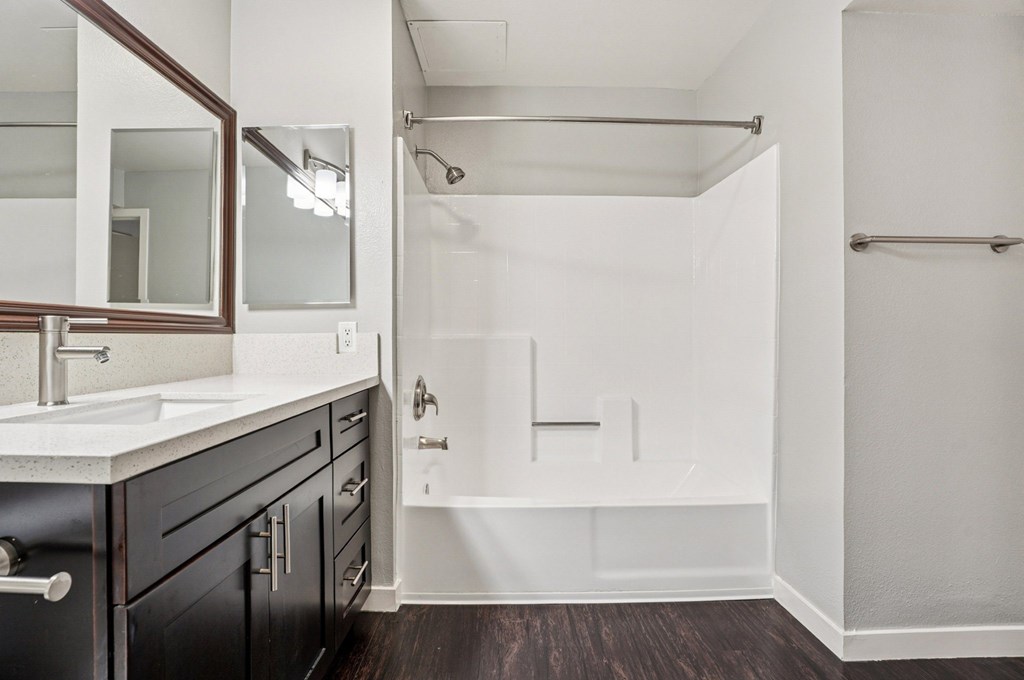 A white bathroom with a black vanity and a walk-in shower.