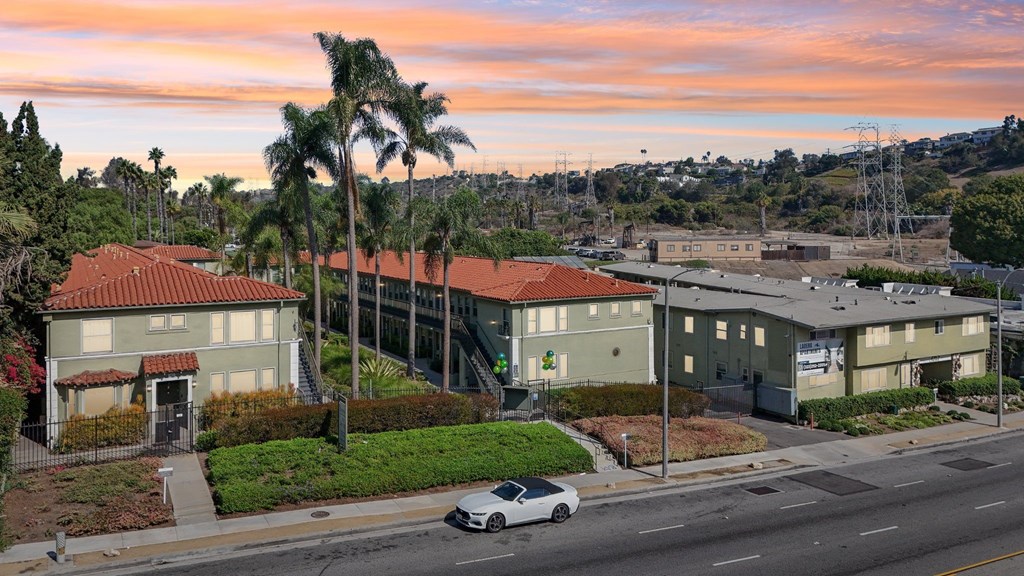 A white car is parked on the side of a street in front of a building.