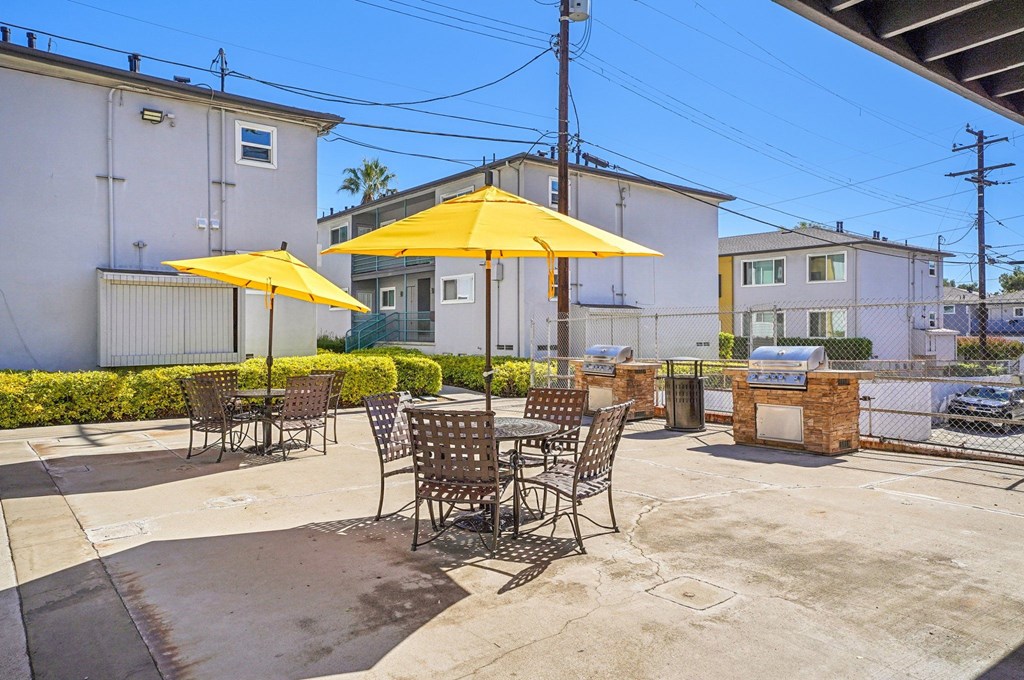 A patio with chairs and a yellow umbrella.