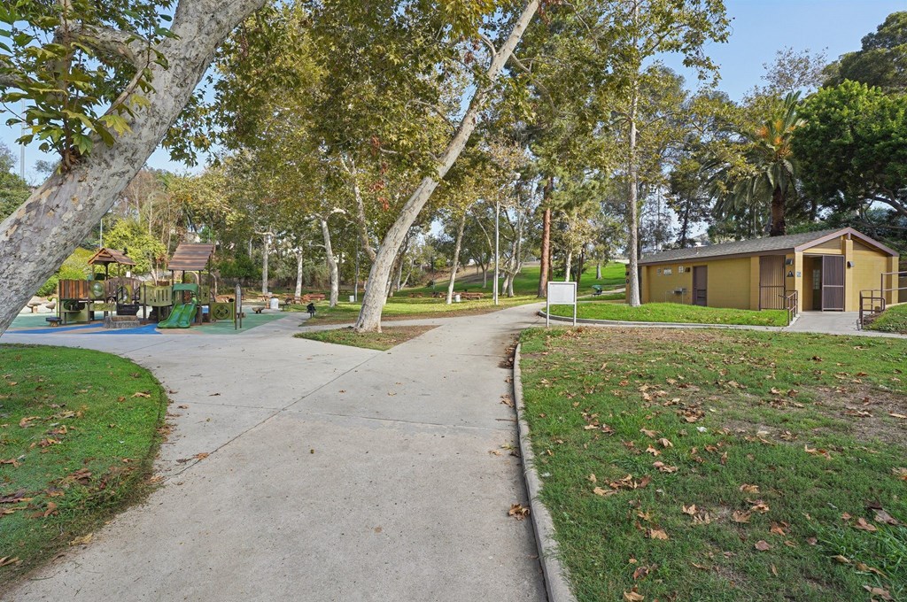 A tree-lined walkway leads to a building in a park.