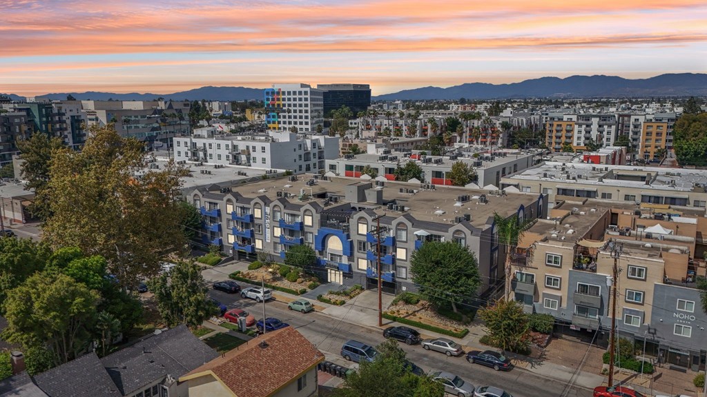 A cityscape with buildings and cars under a pink and blue sky.