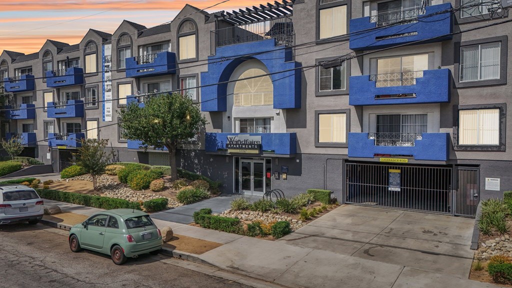 A green car is parked in front of a building with a sign that says "Wandering".