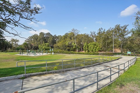 A park with a metal fence and trees in the background.