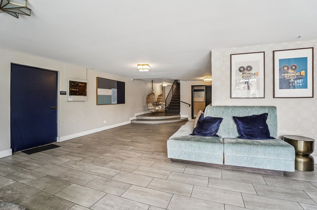 A living room with a blue couch and two pictures on the wall.