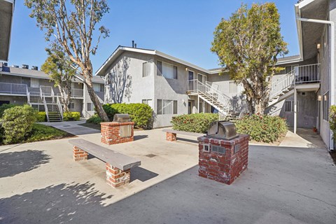 A courtyard with a bench and a tree in front of apartment buildings.