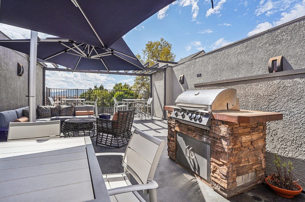 A patio with a stone fireplace and chairs under a canopy.