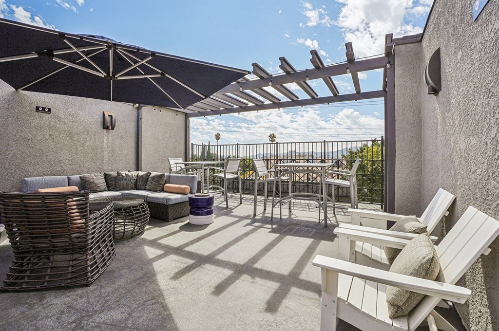 A patio with white chairs and a table is covered by a white awning.