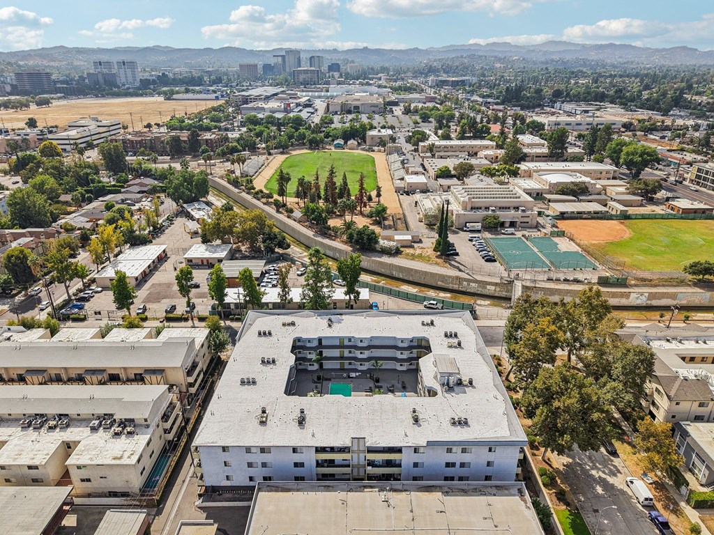 A large white building with a green roof is in the center of a parking lot.