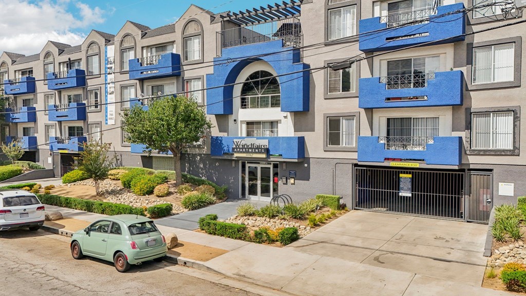 A green car is parked in front of a building with a blue and white facade.