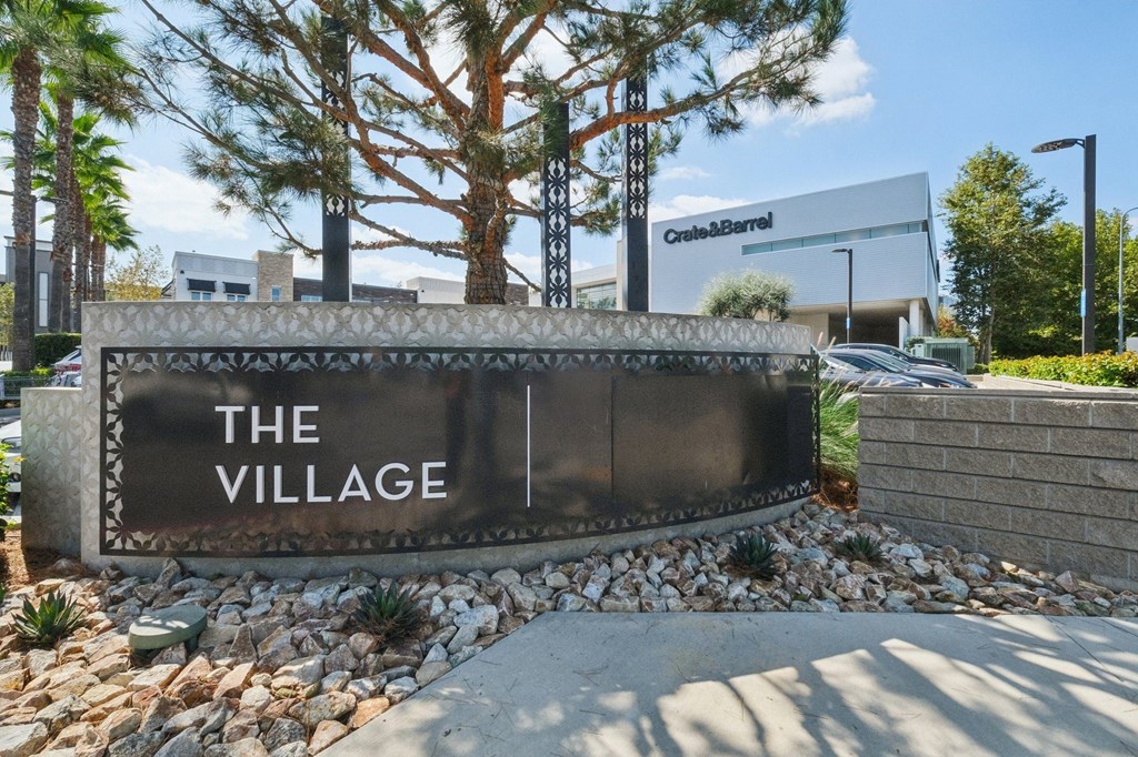 A sign that says "The Village" in front of a building.