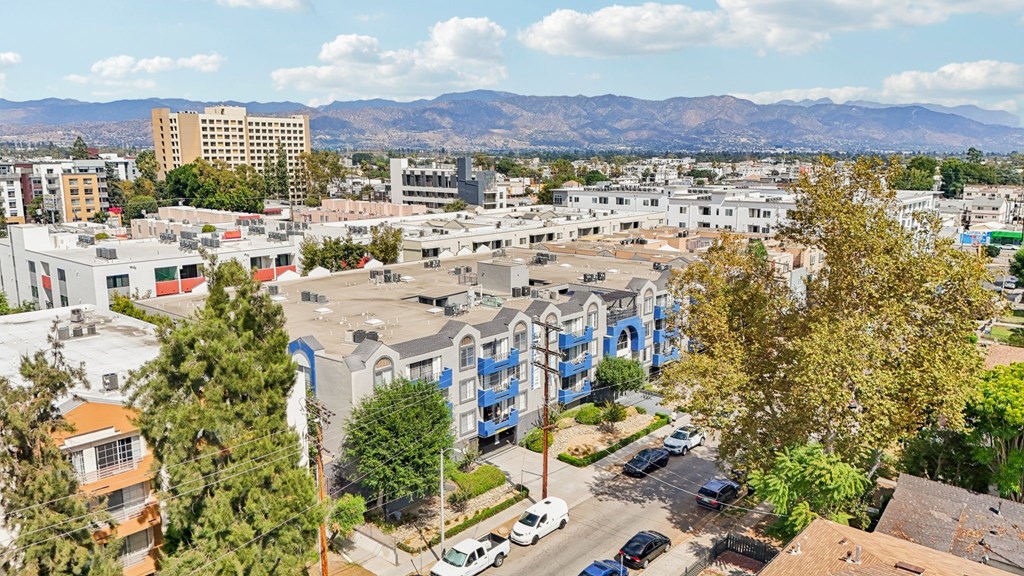 A cityscape with buildings, cars, and trees under a blue sky.