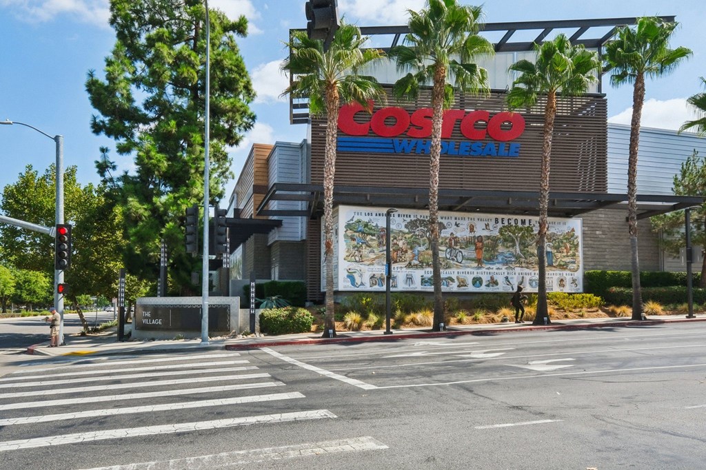 A Costco store is located on a street corner with a crosswalk in front.