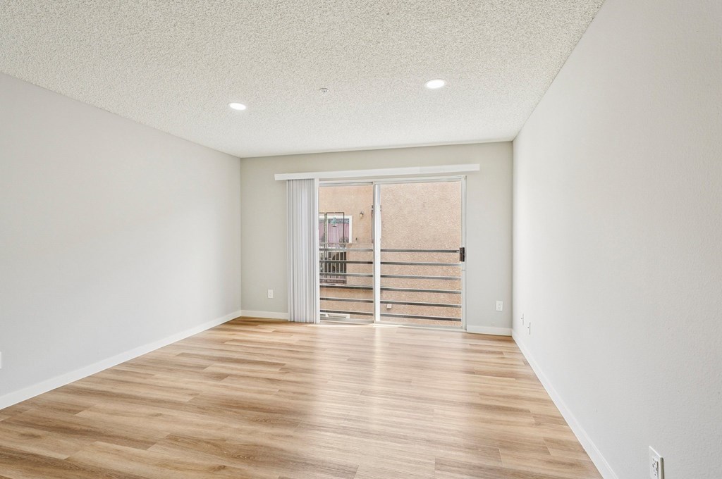 A room with wooden flooring and a sliding glass door.