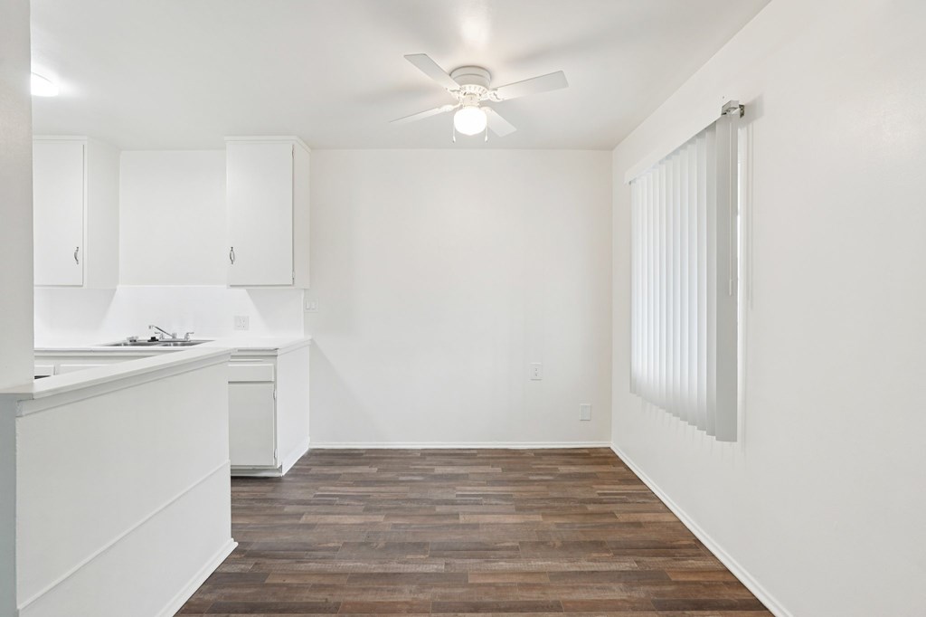 A kitchen with white cabinets and a wooden floor.