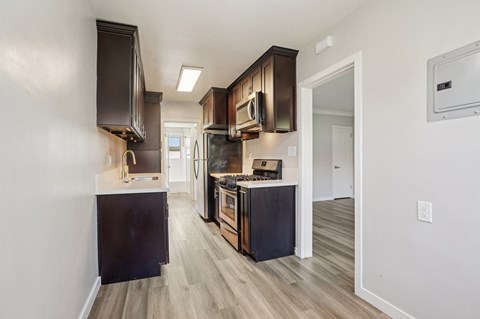 A kitchen with dark wood cabinets and a black refrigerator.