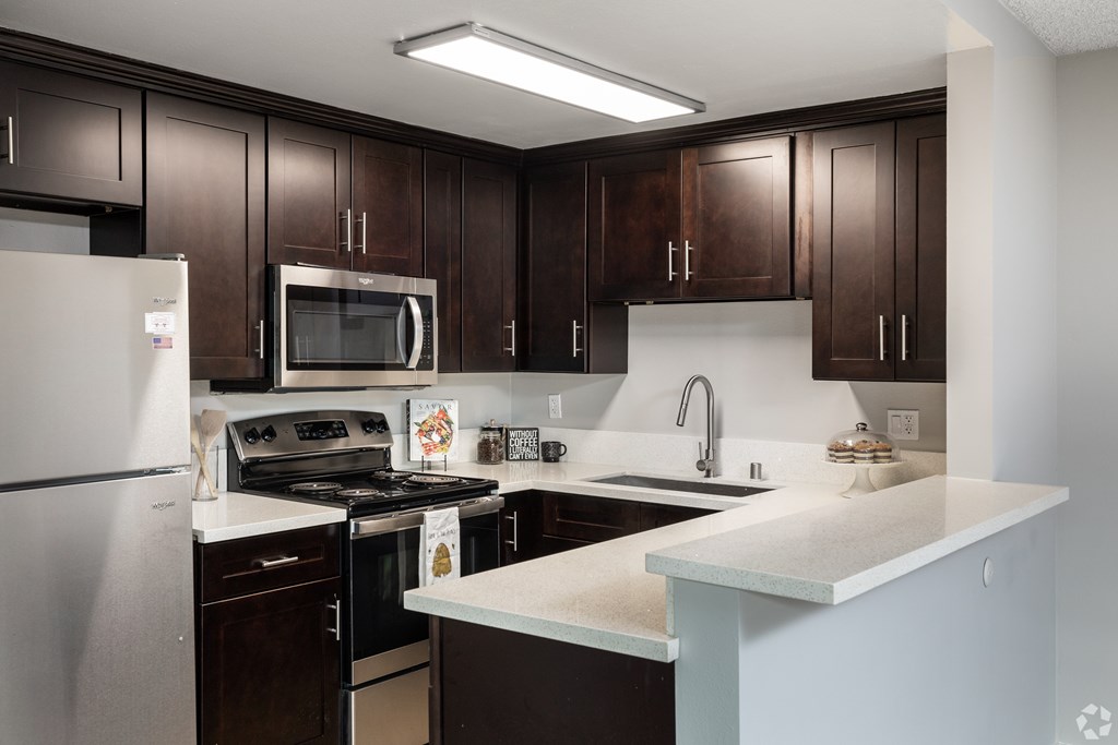 A kitchen with dark brown cabinets and a white counter.