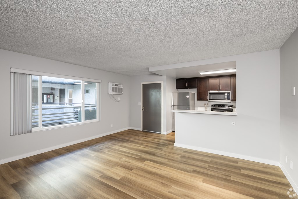 A spacious room with wooden flooring and a kitchenette.