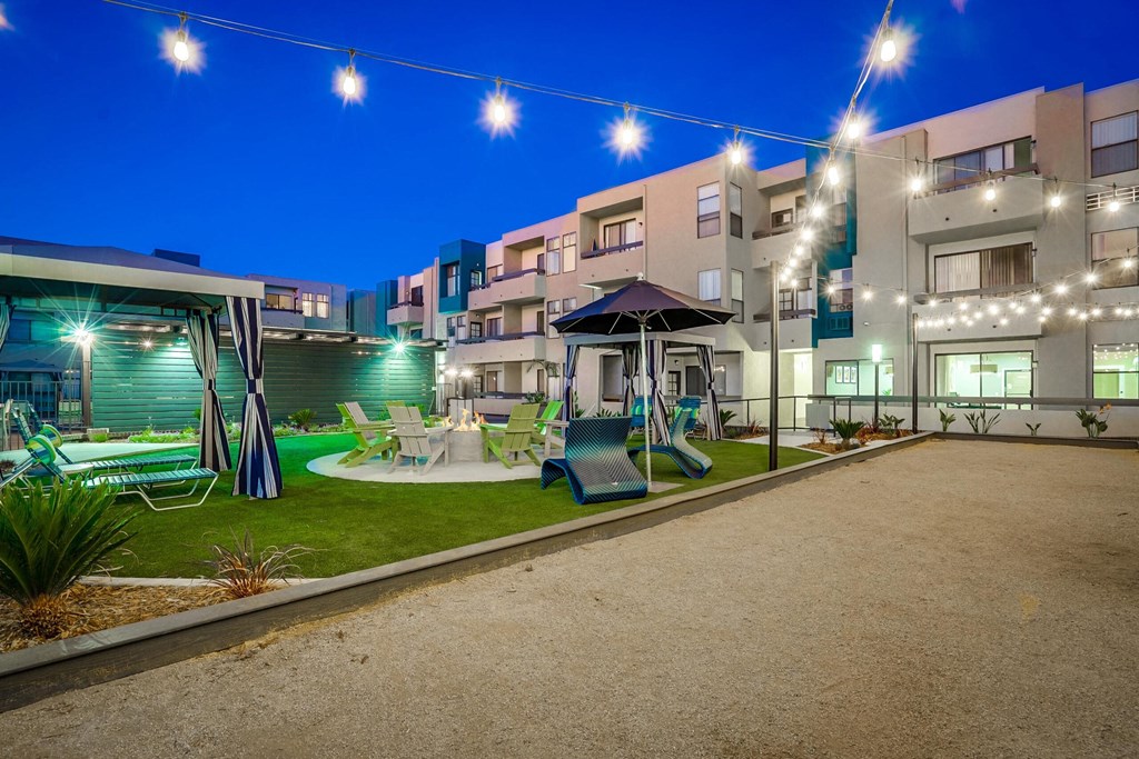 a courtyard with swings and lawn furniture at night