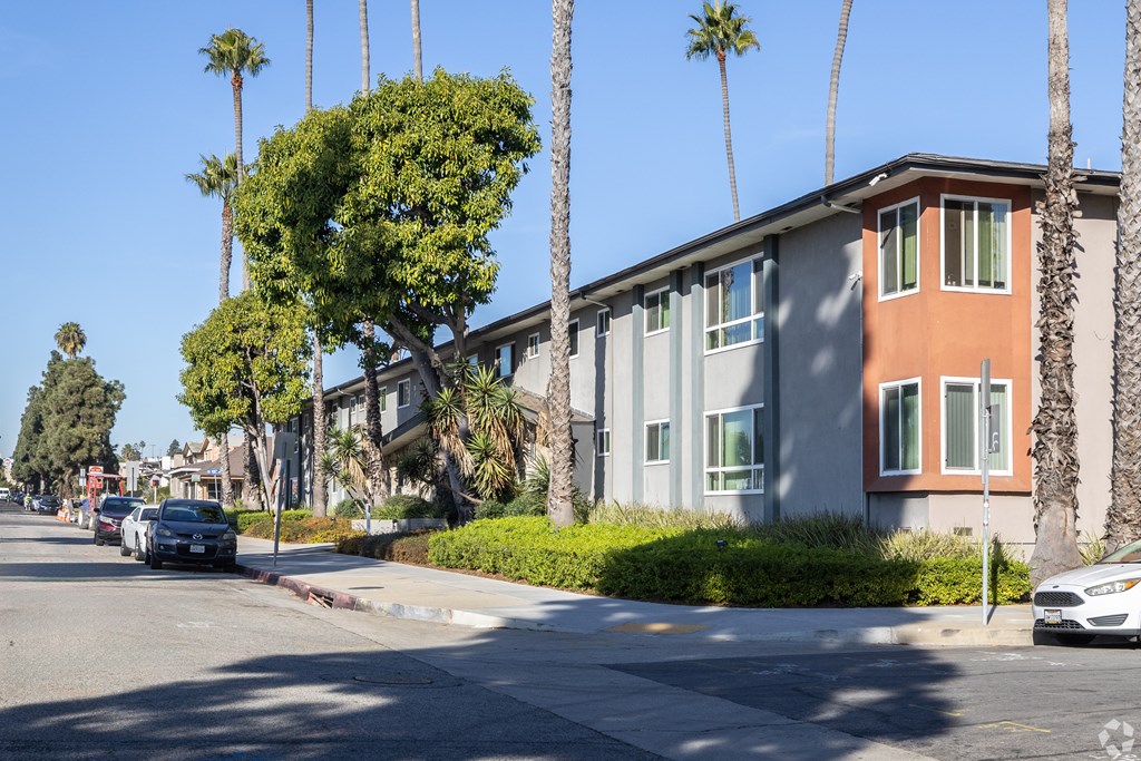 A street view of a residential area with cars parked on the side of the road.