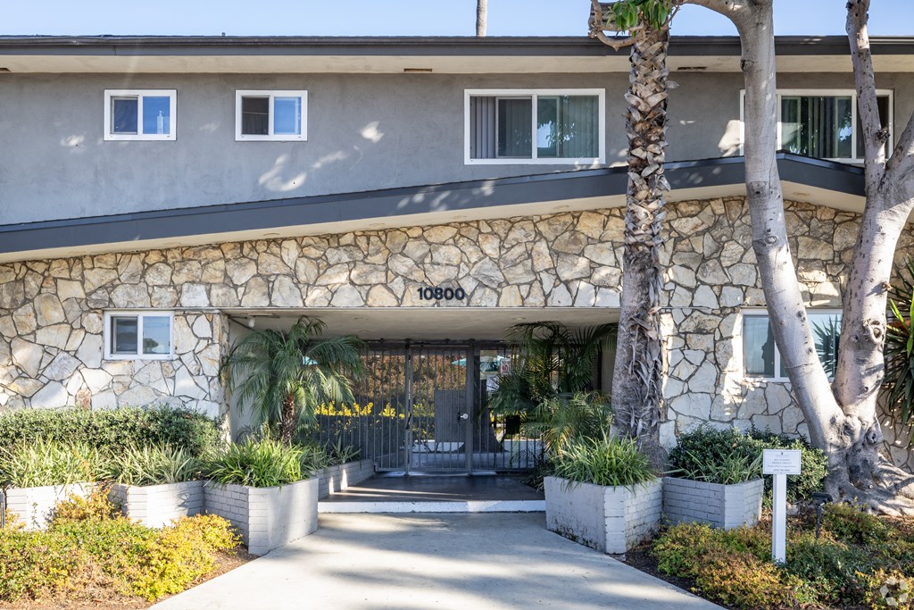 A building with a stone wall and a tree in front.