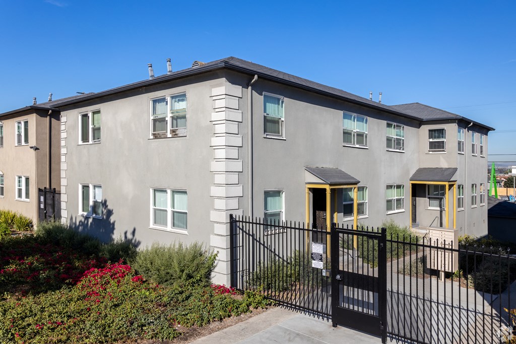 A grey building with a black fence and gate in front.