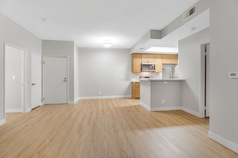 A spacious room with wooden flooring and white walls.