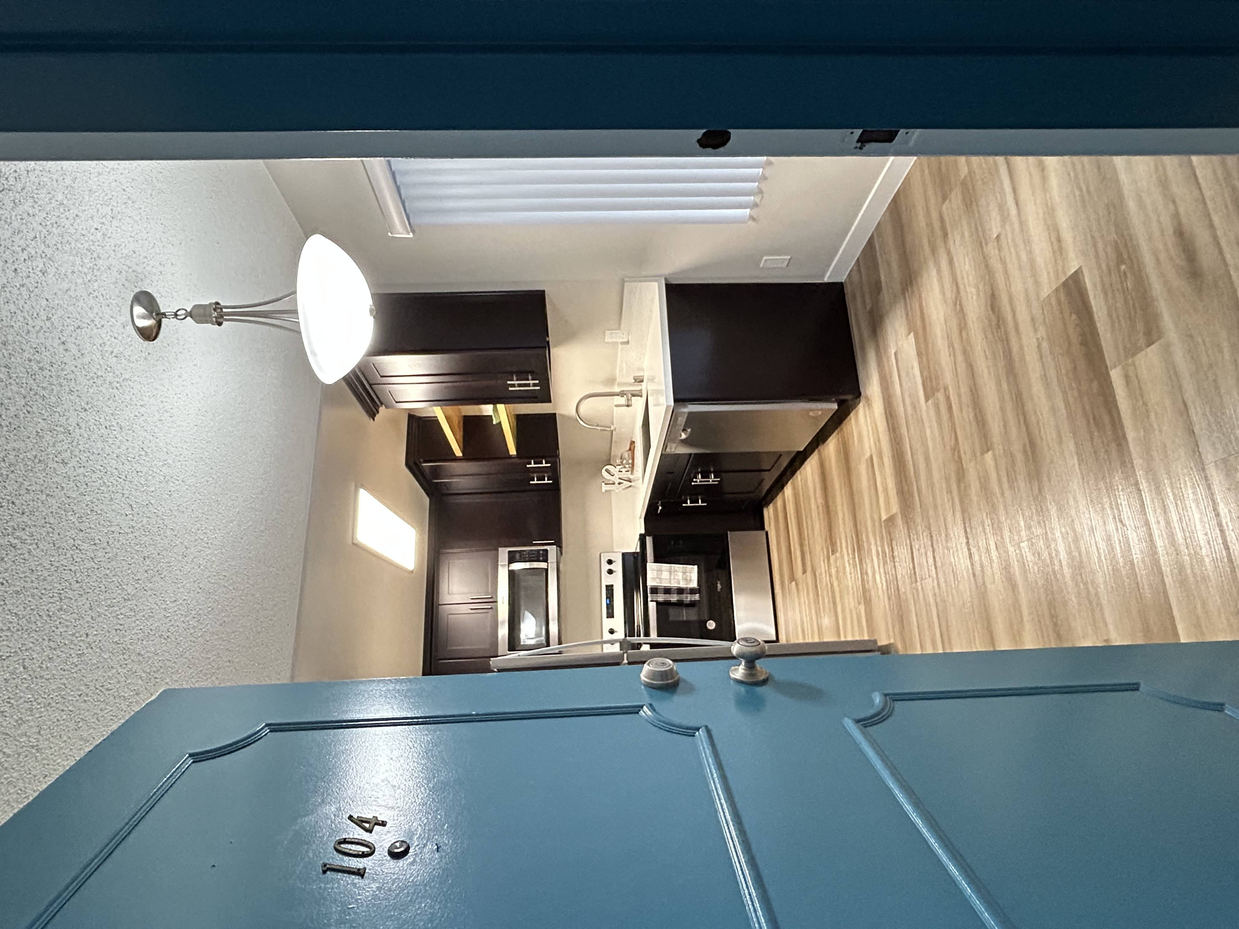 A compact, fully upgraded kitchen in a modern studio apartment, featuring sleek countertops, stainless steel appliances, and ample storage space