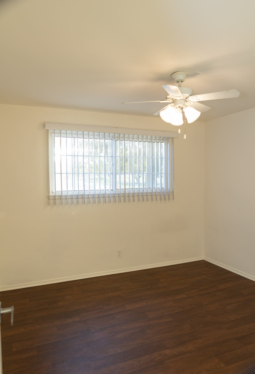 an empty living room with a ceiling fan and a window