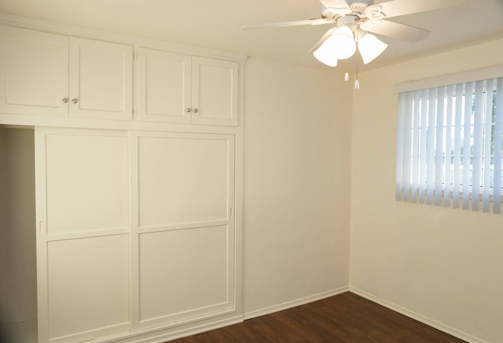 a bedroom with white walls and a ceiling fan