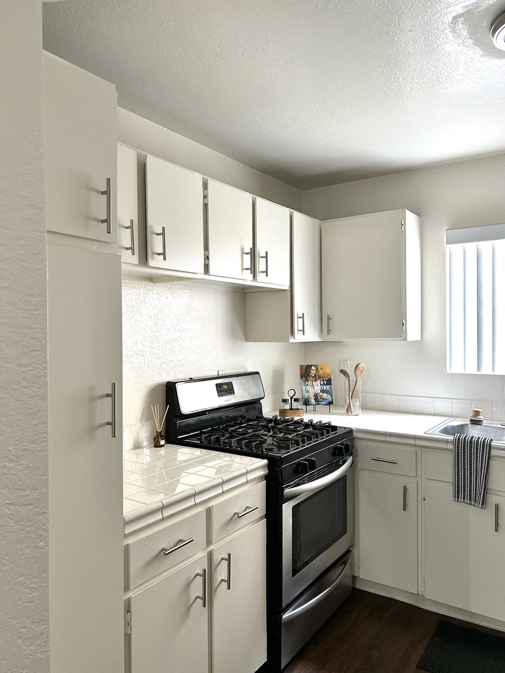 an empty kitchen with white cabinets and a black stove