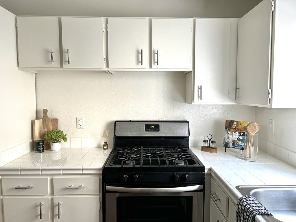 a kitchen with white cabinets and a stove and a sink