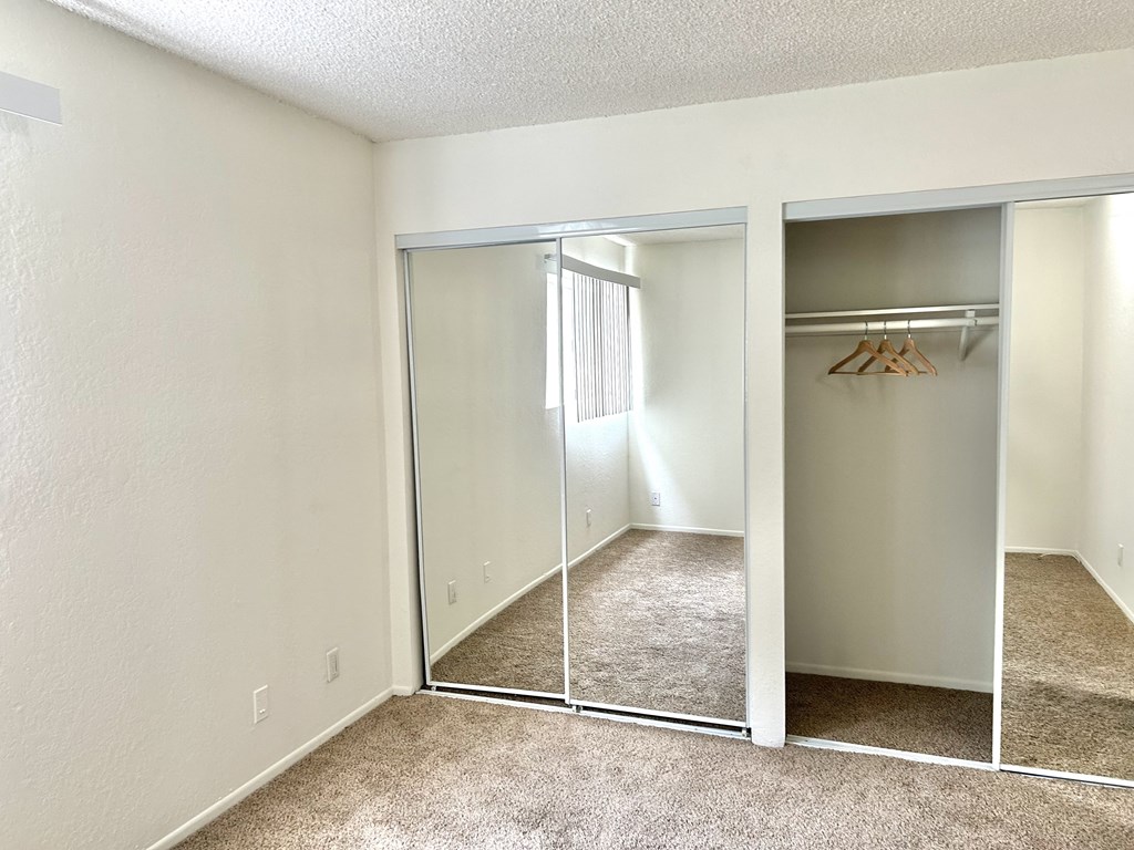 an empty bedroom with mirrored closet doors and carpeted flooring