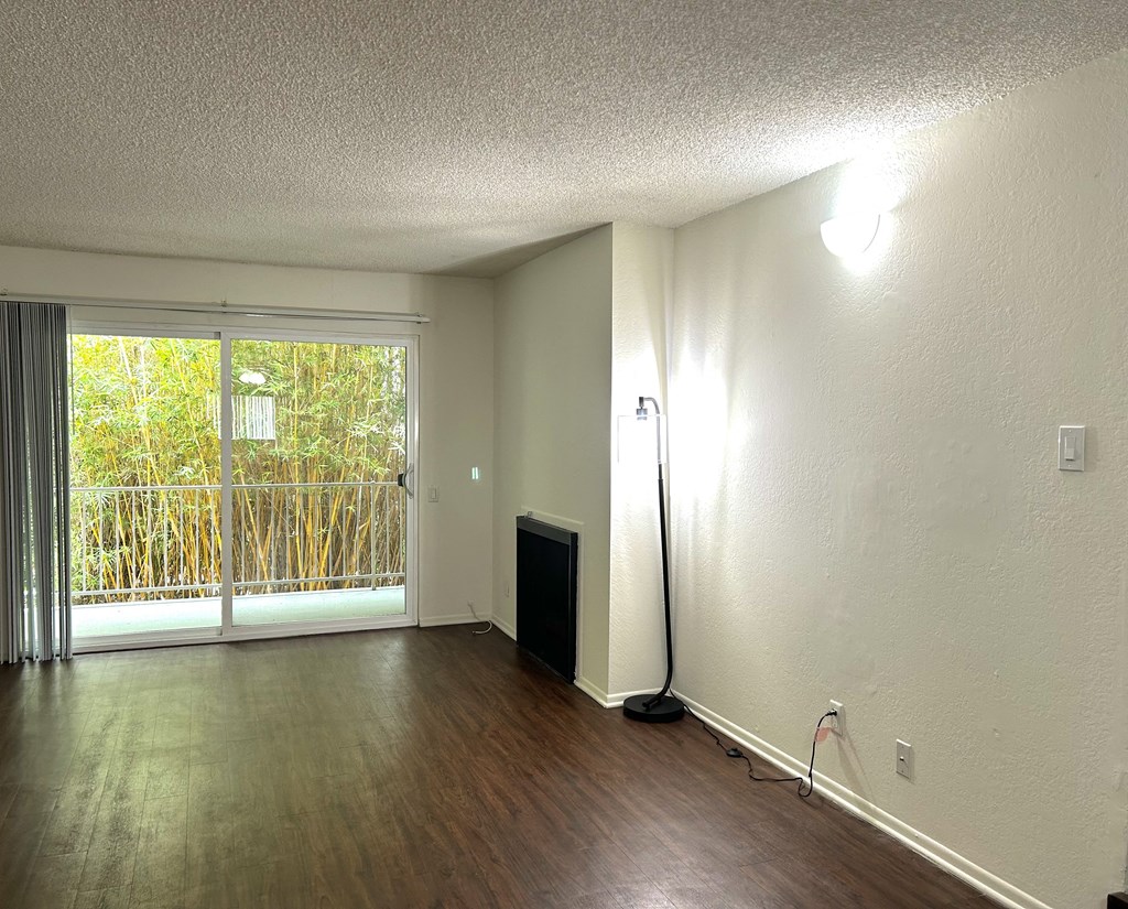 an empty living room with wood floors and a sliding glass door